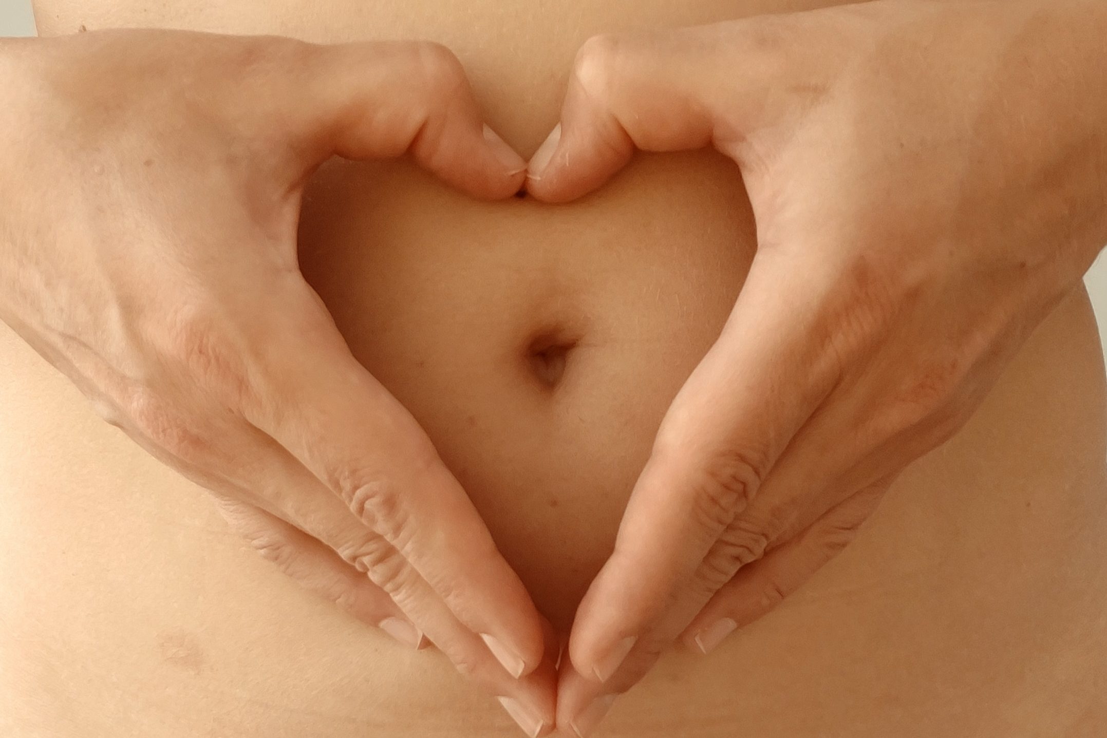 Hände formen ein Herz vor einem Körper